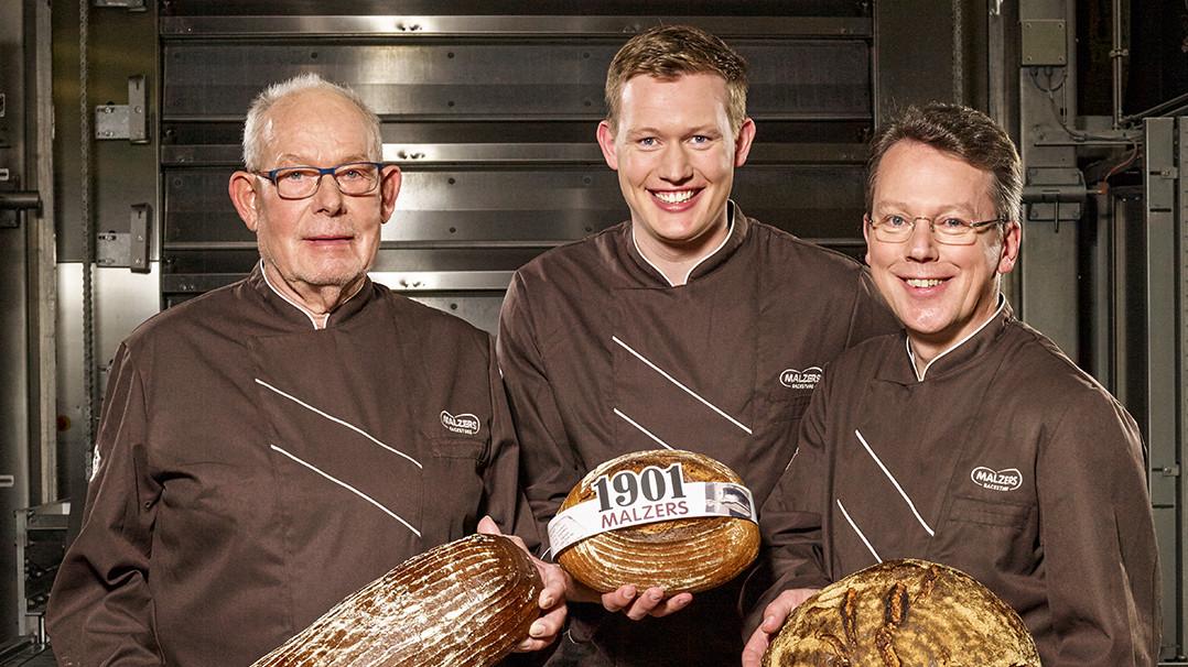 Herbert Wortmann, Christian und Hans-Joachim Scherpel halten Malzers Brote in den Händen