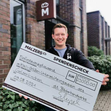 Christian Scherpel hält Spendencheck in Händen